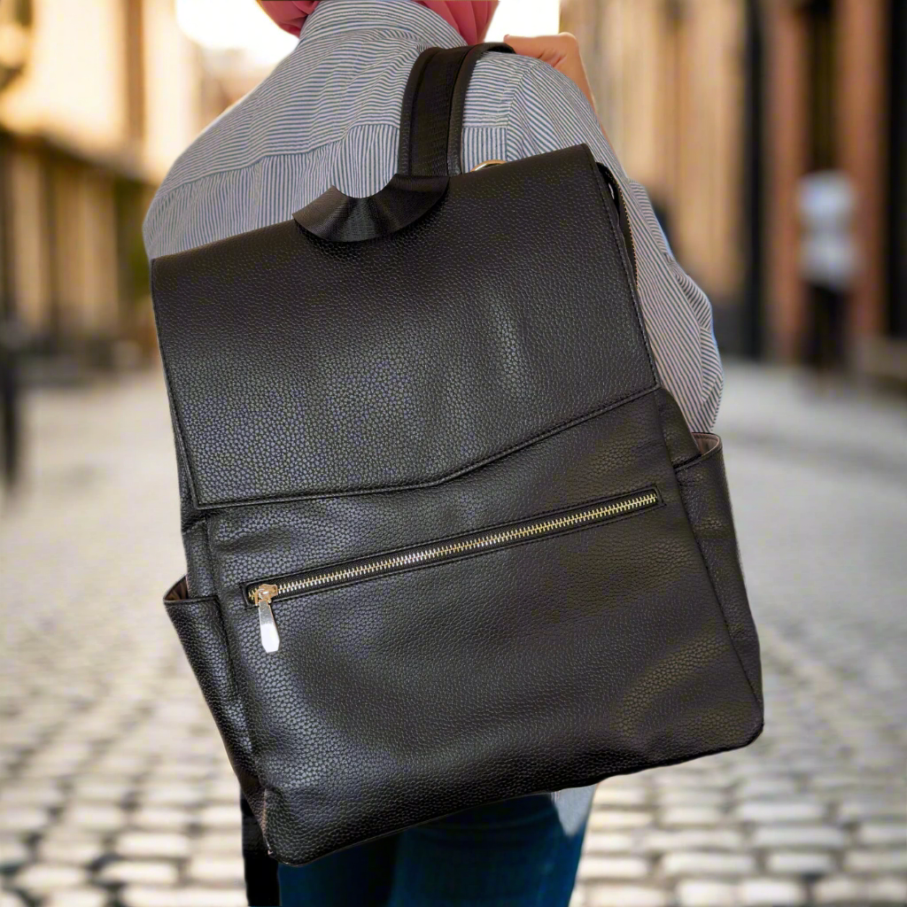 Person wearing a black leather backpack on a plain background